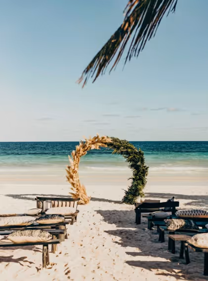 Arco nupcial bohemio en la playa de arena blanca del hotel La Valise Tulum, México.