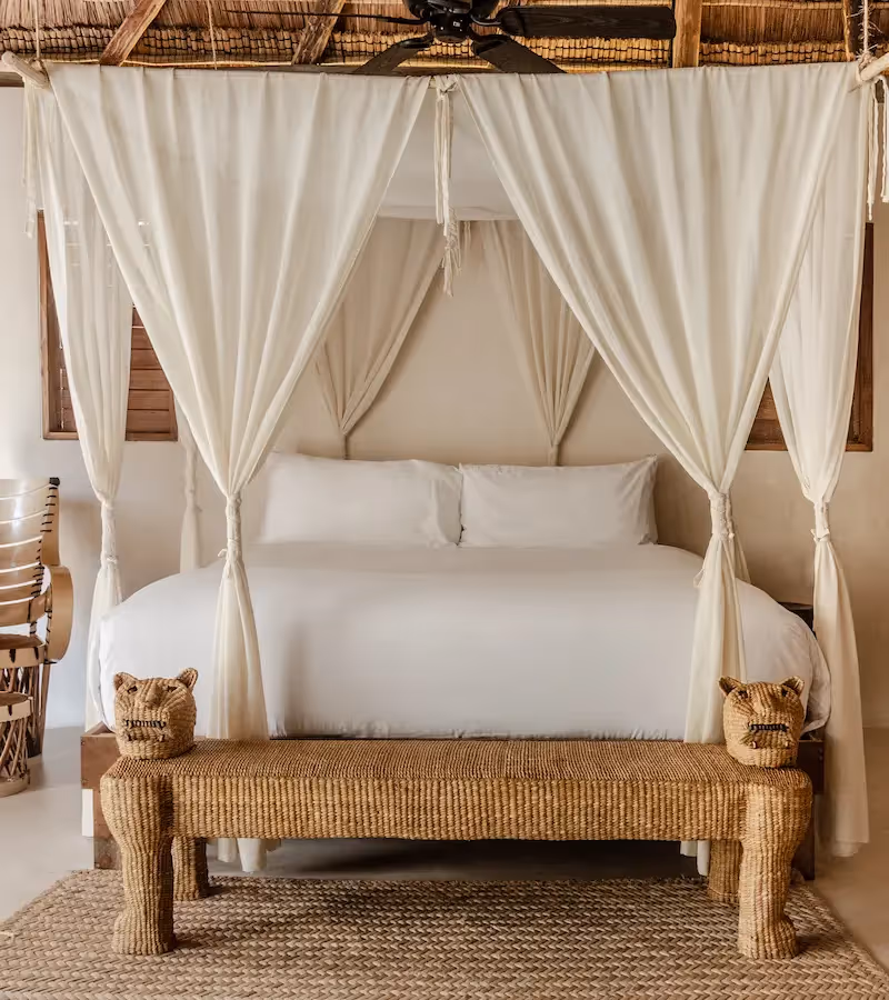 Luxurious bedroom at La Valise Tulum hotel featuring a white canopy bed, elegant curtains, and artisanal decor in Mexico.