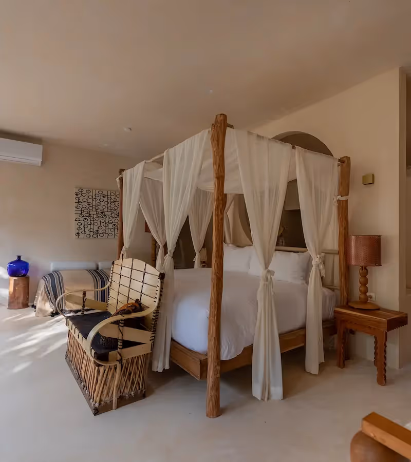 Luxury guest room featuring a four-poster canopy bed with white linens at La Valise Tulum hotel, Mexico.