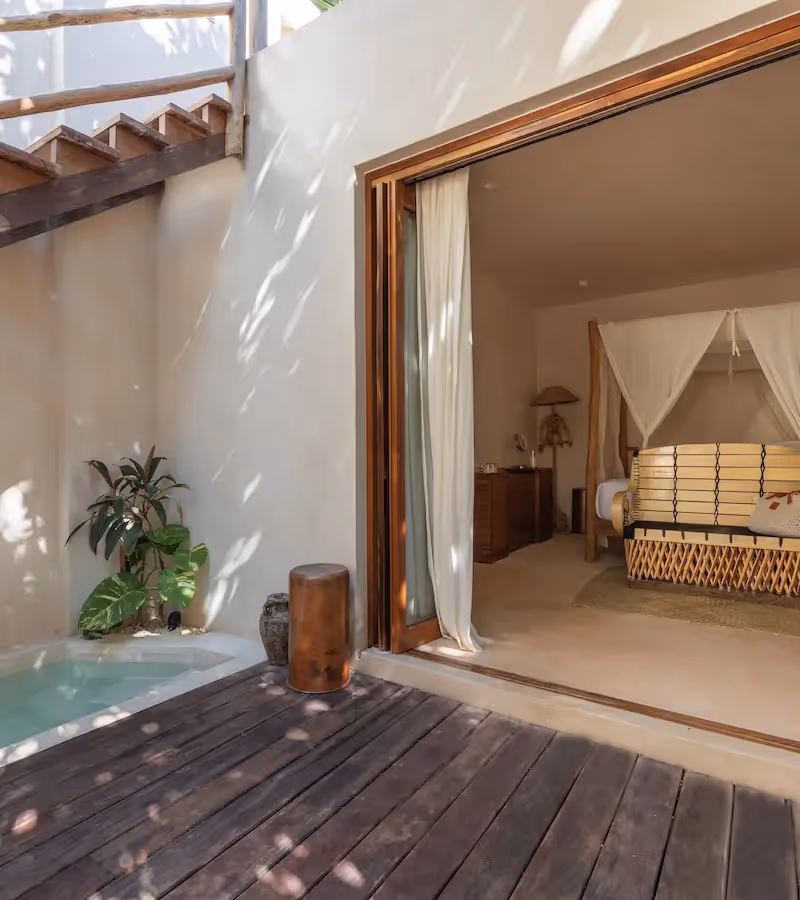 Luxury suite at La Valise Tulum featuring a private plunge pool and seamless indoor-outdoor access to a canopy bed bedroom.