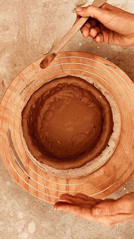Hand-on pottery workshop at La Valise Tulum Hotel: hands kneading raw clay for a cultural and holistic experience in Mexico.