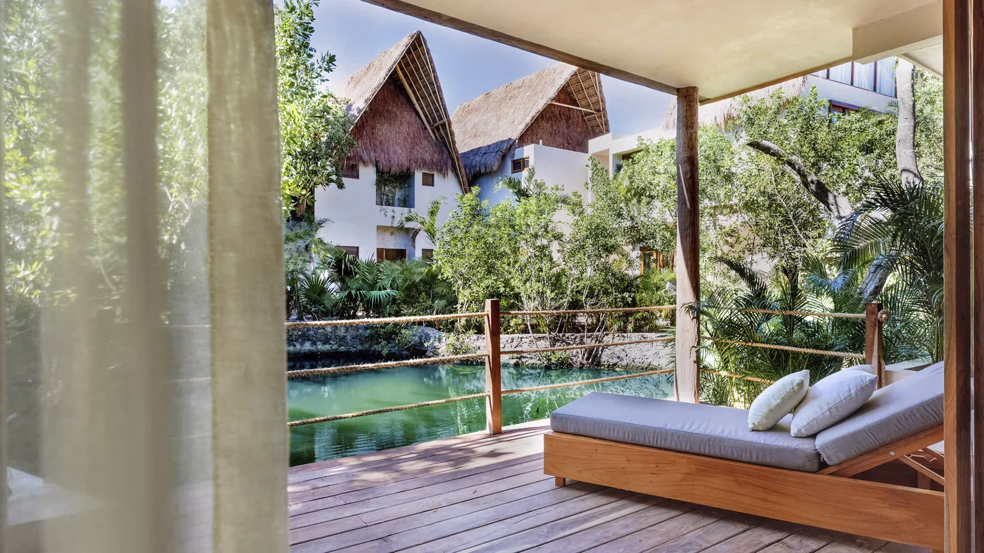 Iconic outdoor bed on a wooden deck surrounded by tropical jungle at La Valise Tulum hotel, Mexico.