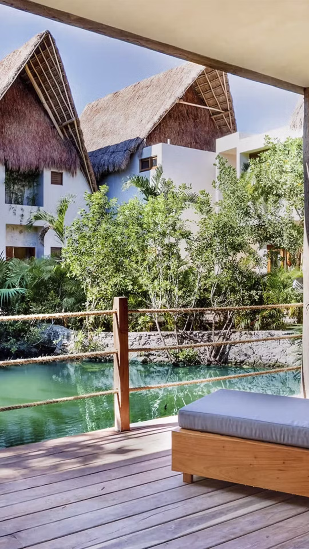 Iconic outdoor bed on a wooden deck surrounded by tropical jungle at La Valise Tulum hotel, Mexico.