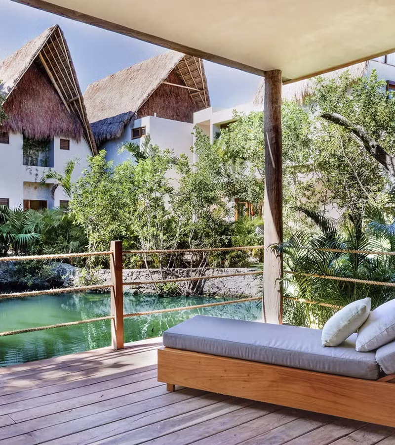 Iconic outdoor bed on a wooden deck surrounded by tropical jungle at La Valise Tulum hotel, Mexico.