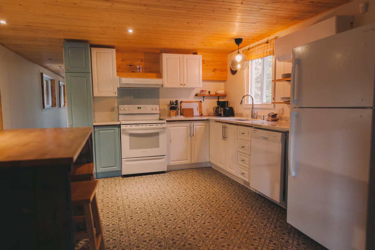 Cuisine équipée du chalet Le Phoenix avec armoires blanches et réfrigérateur en inox