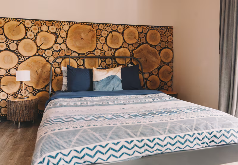 Chambre 1 du chalet Le Phoenix, lit double devant un mur de rondins de bois