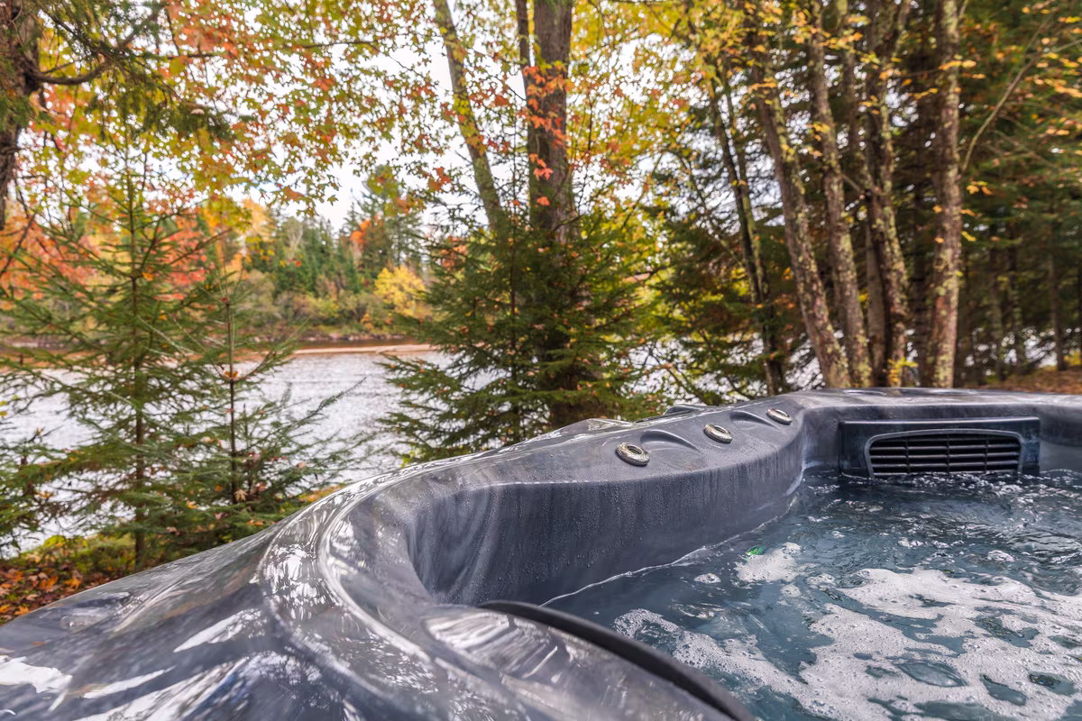 Spa privé du chalet Le Phoenix face à la rivière, en automne