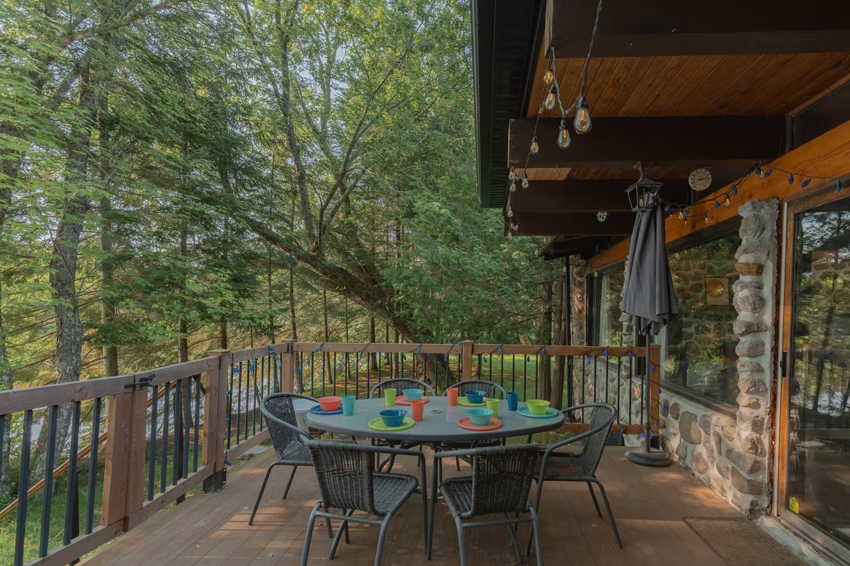 Terrasse couverte du chalet Le Phoenix avec table à manger extérieure en forêt