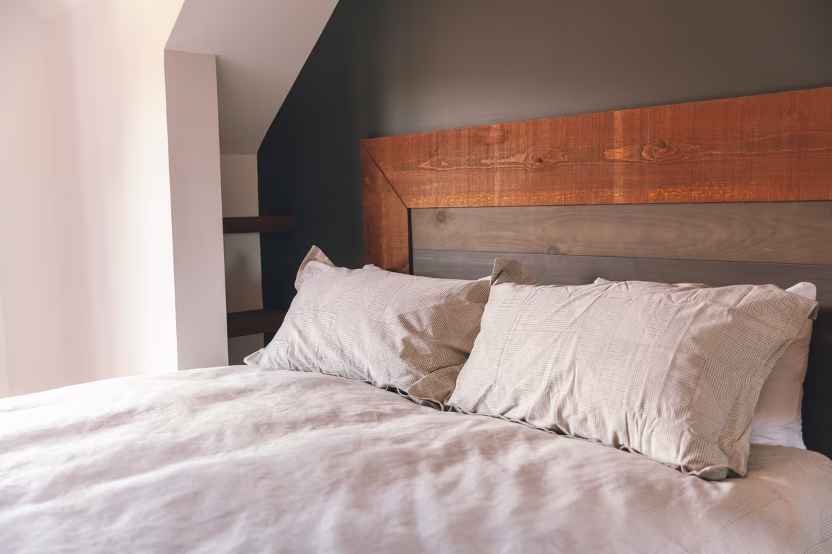 Chambre 3 du chalet L'Ours Noir, très grand lit et tête de lit en bois sur mur foncé