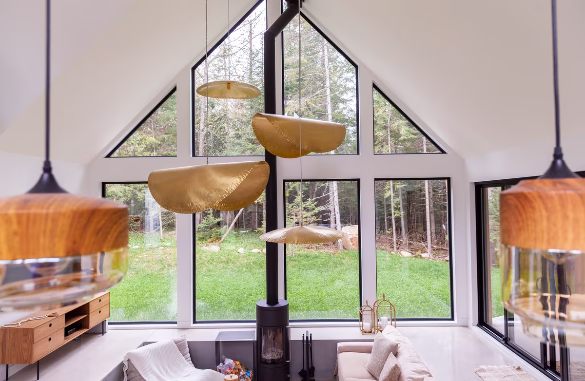 Salon du chalet Halona sous une grande fenêtre en pignon ouverte sur la forêt