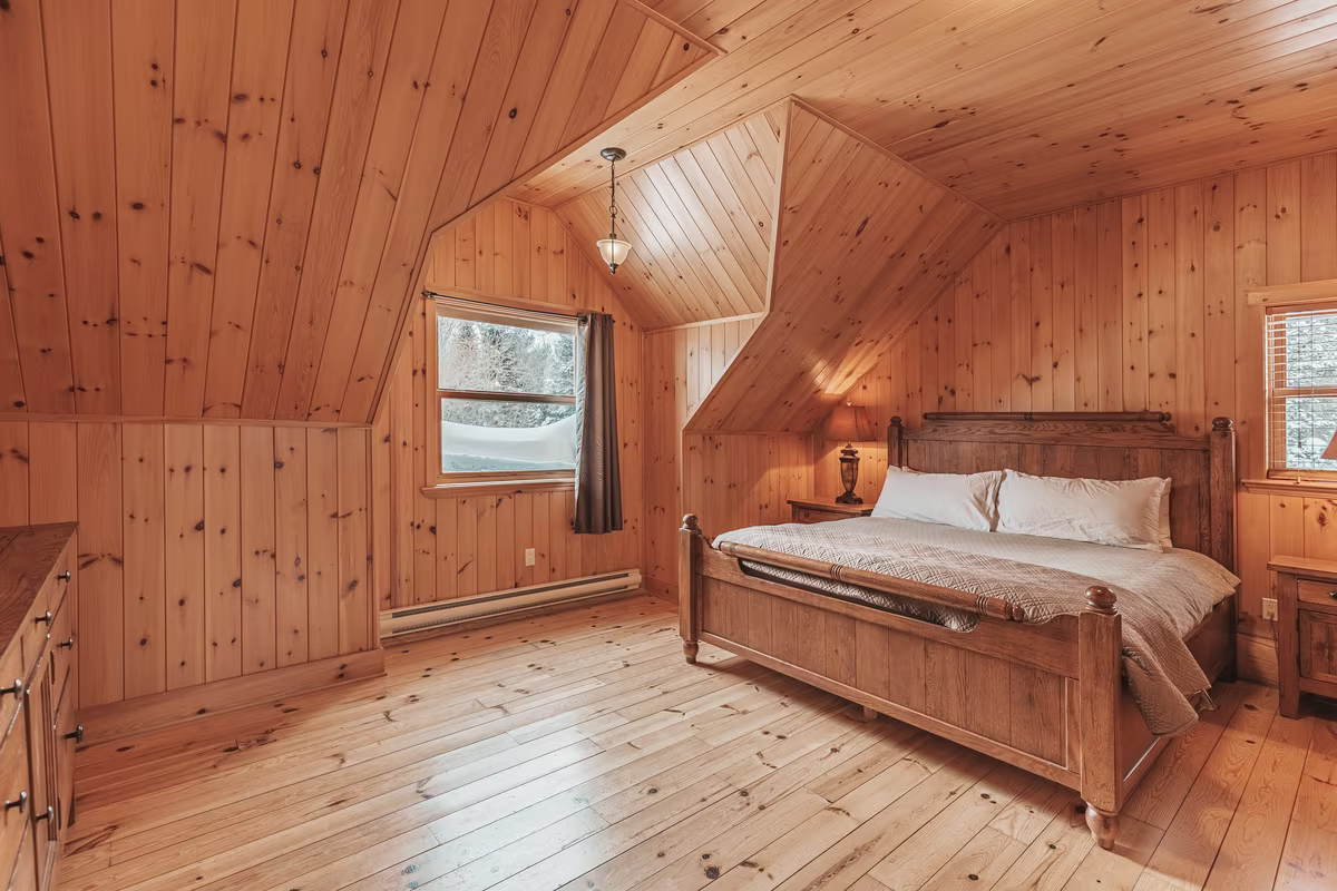 Chambre 2 du chalet Exécutif Double, lit King en bois sous plafond en pente