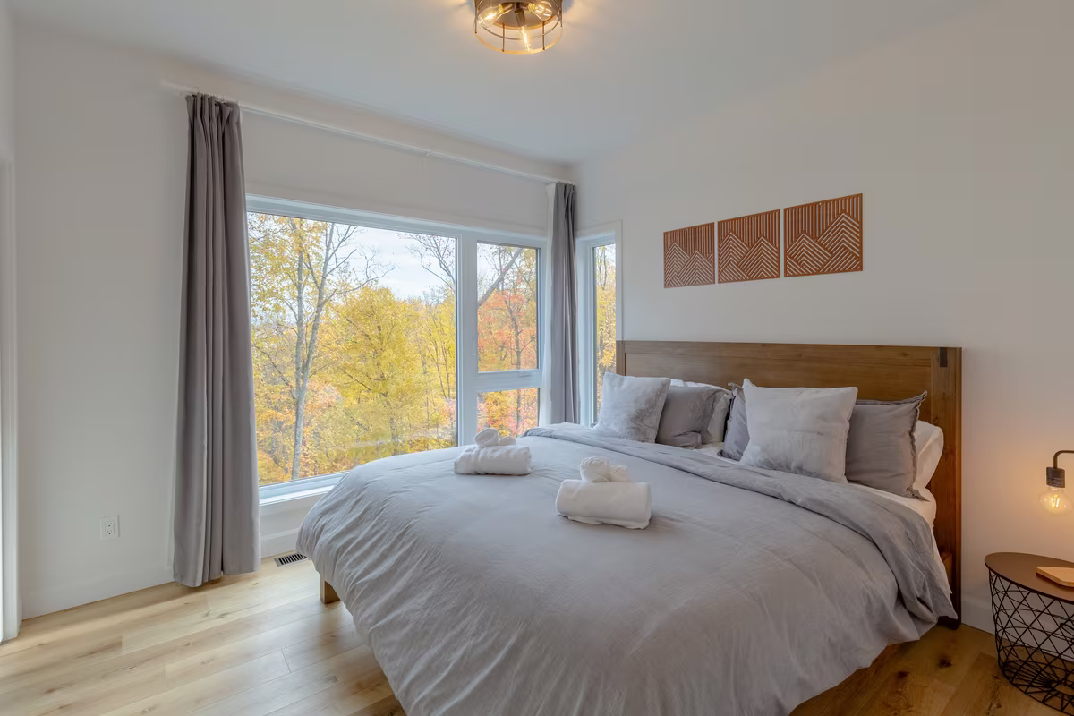 Chambre 1 du chalet LIV Tremblant, très grand lit et grande fenêtre sur la forêt