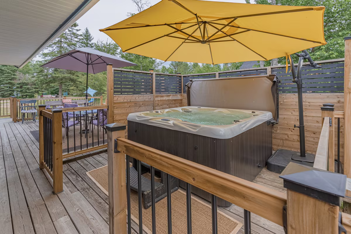 Spa privé sur la terrasse du chalet Fox Lodge sous un parasol