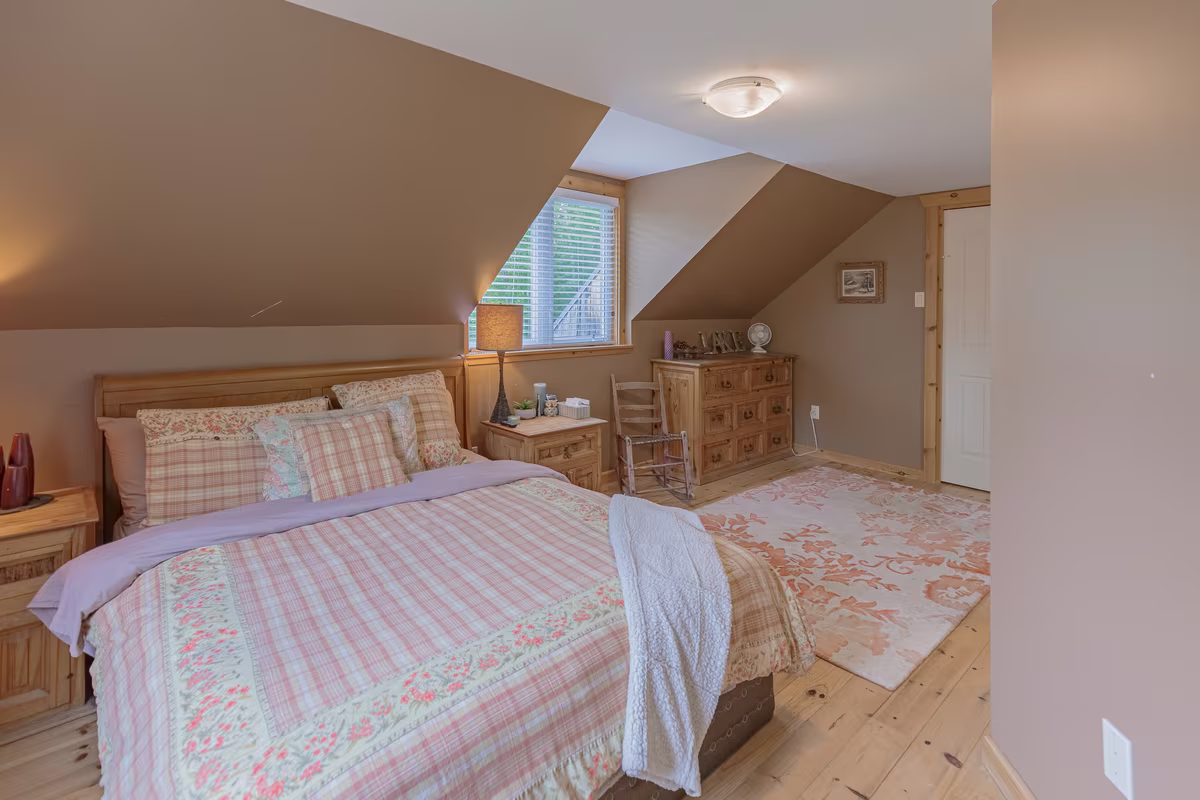 Chambre 3 du chalet Fox Lodge, lit sous plafond mansardé et chaise berçante