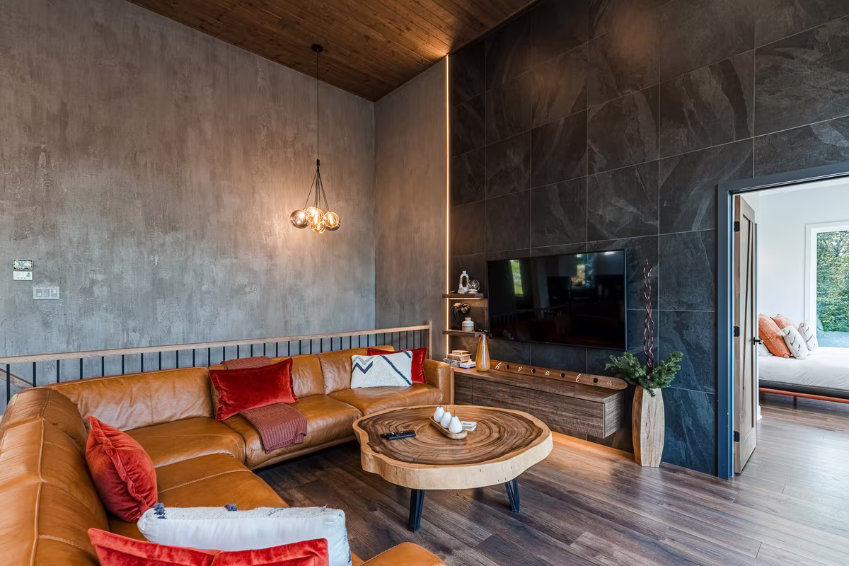 Salon du chalet Avala avec canapés en cuir et mur de pierre foncée