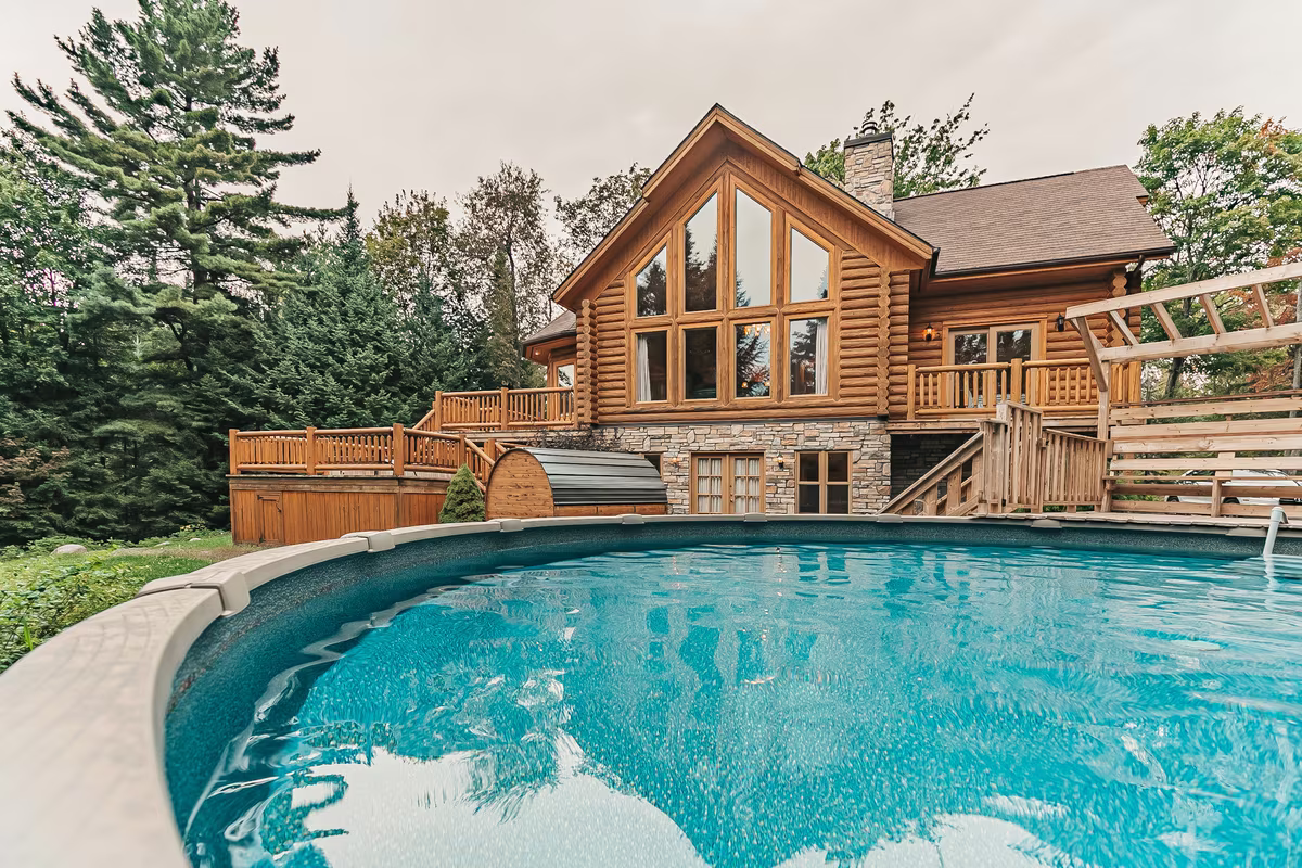 Piscine hors terre et façade en bois rond du chalet Harfang