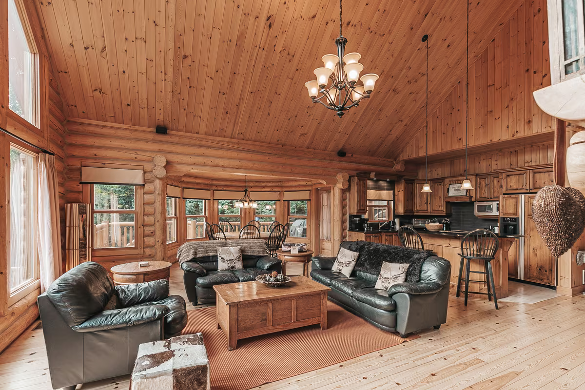 Grande pièce du chalet Harfang avec plafond cathédrale en bois et canapés en cuir