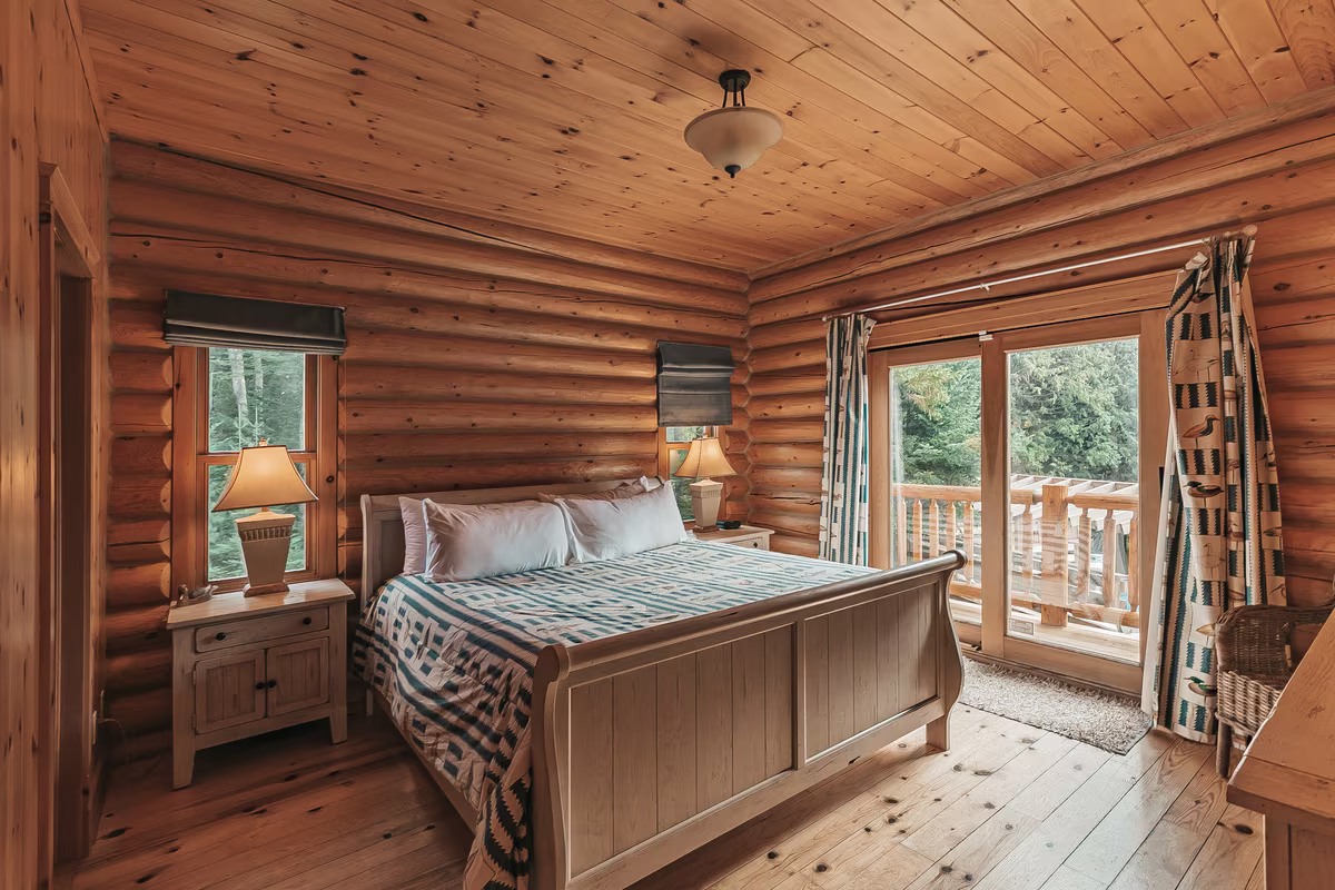 Chambre 1 du chalet Harfang, très grand lit et porte-fenêtre en bois rond