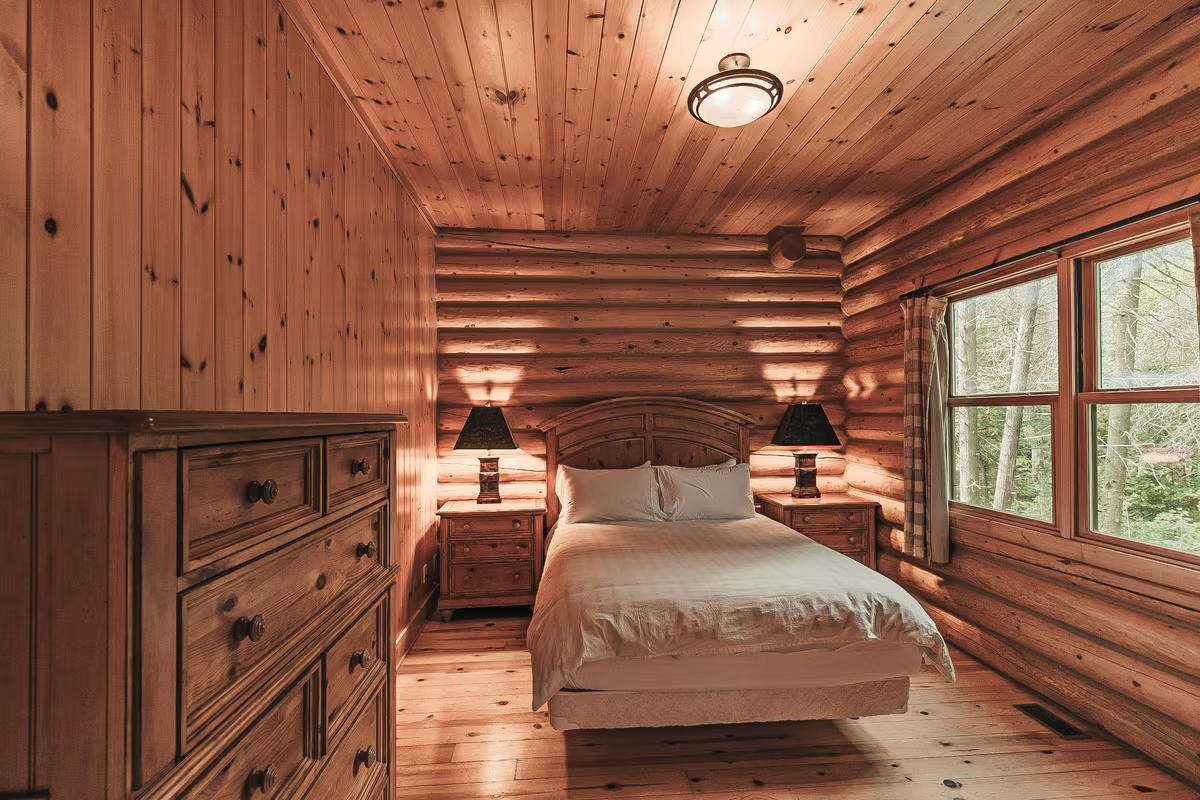 Chambre 5 du chalet Harfang, grand lit dans une pièce en bois rond