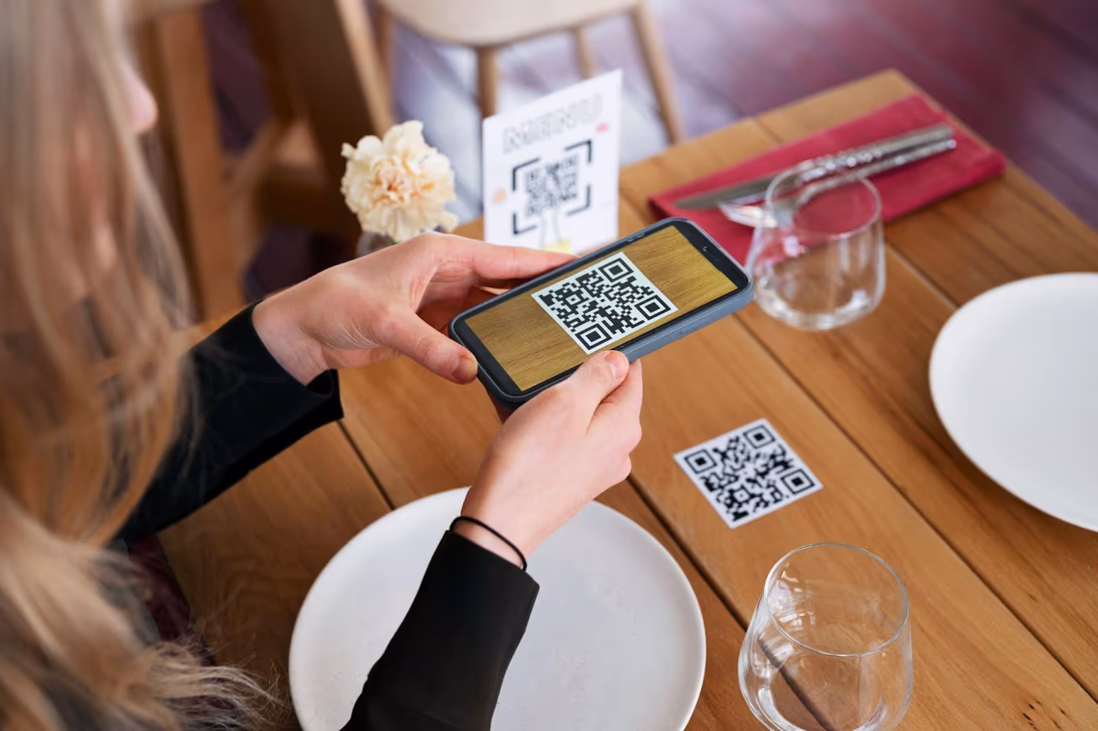 Woman sitting at a table scanning a QR code with her phone.