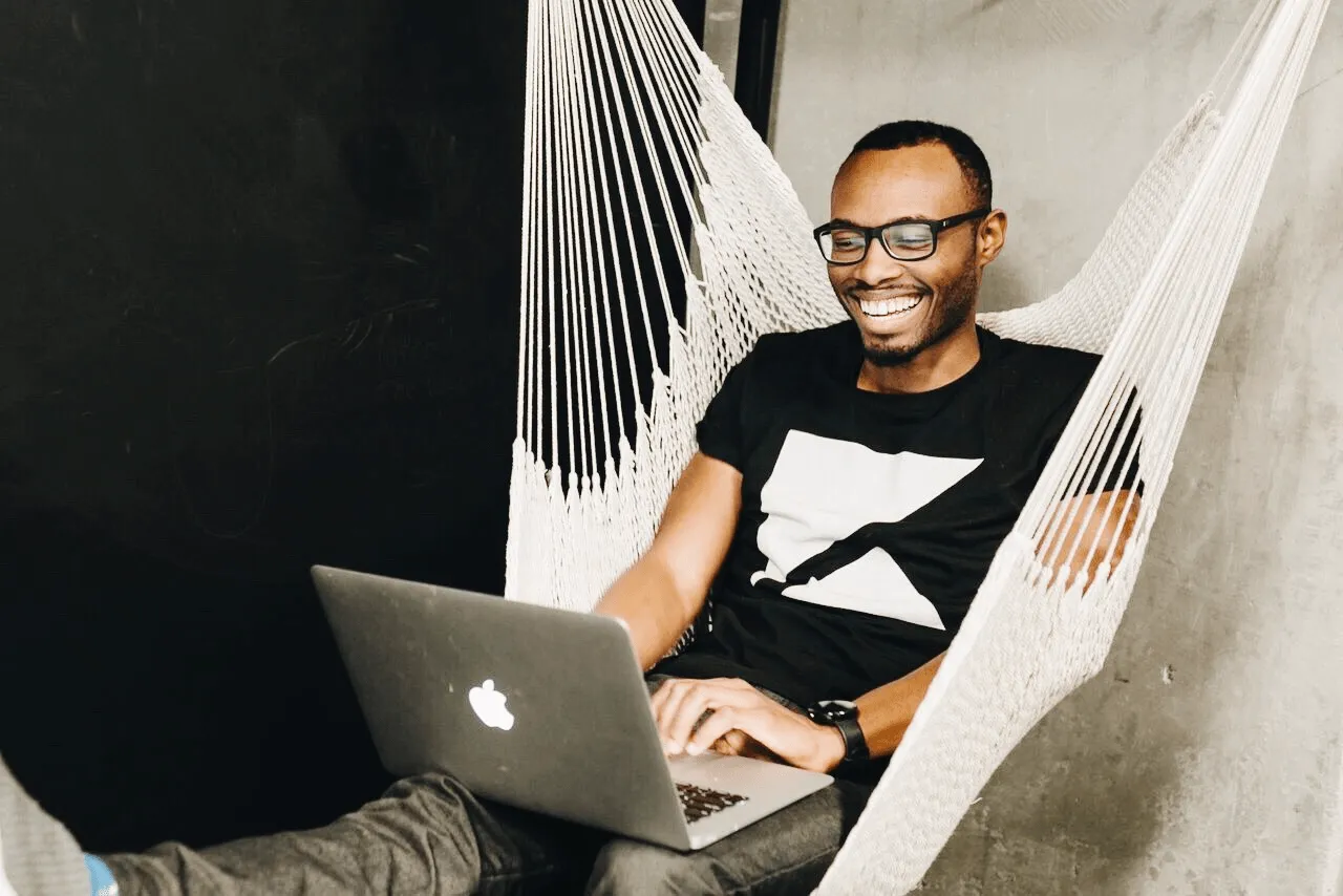 Image of Jamell Jones working on a laptop in a swinging chair 