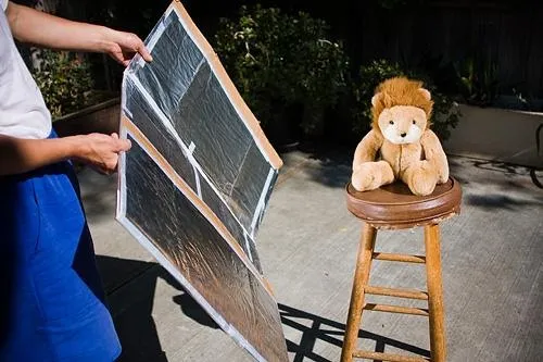 Photographer uses foil taped to cardboard to create fill lighting on photo subject
