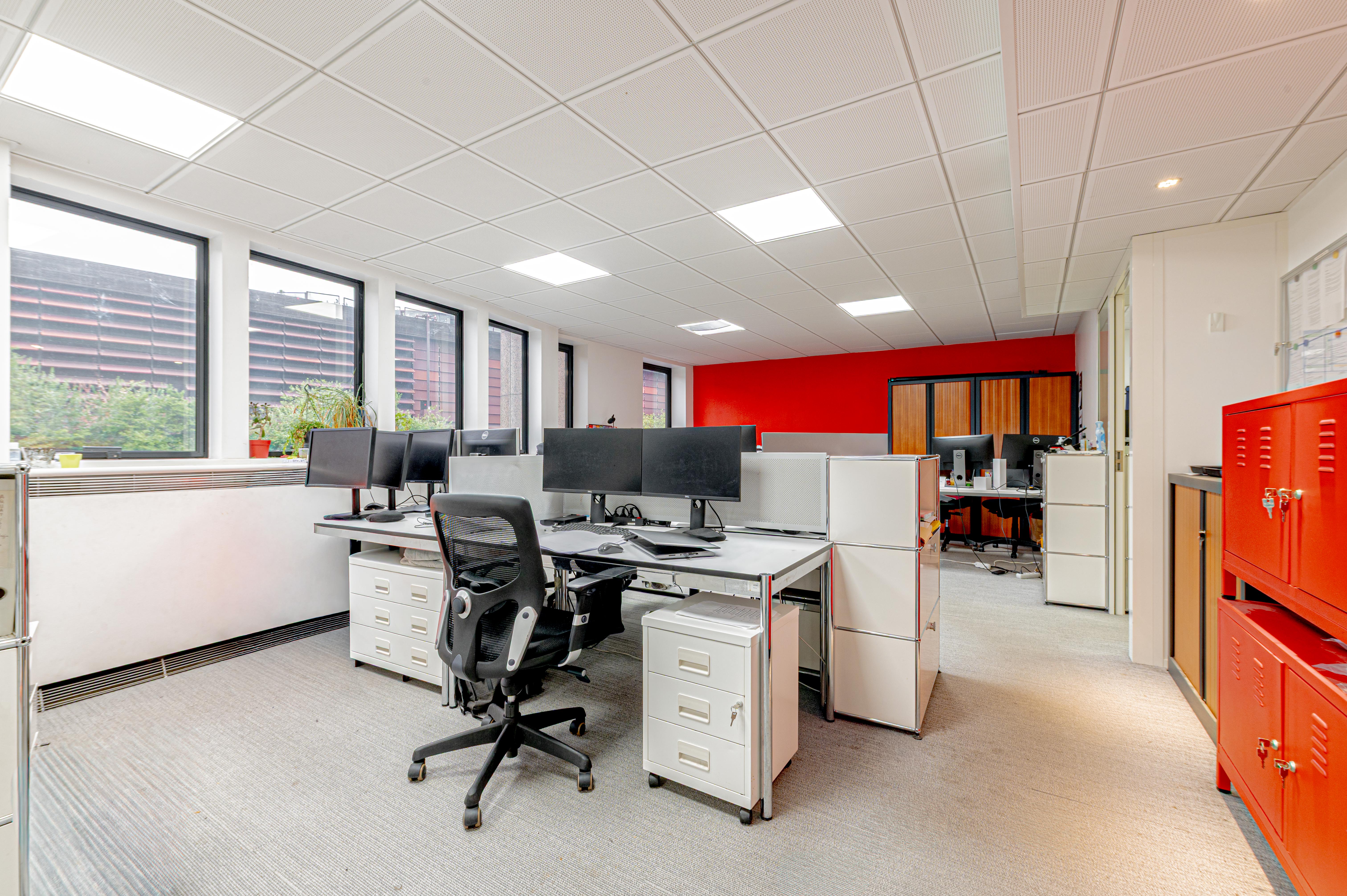 deux open spaces avec des bureaux et des chaises et une cuisine