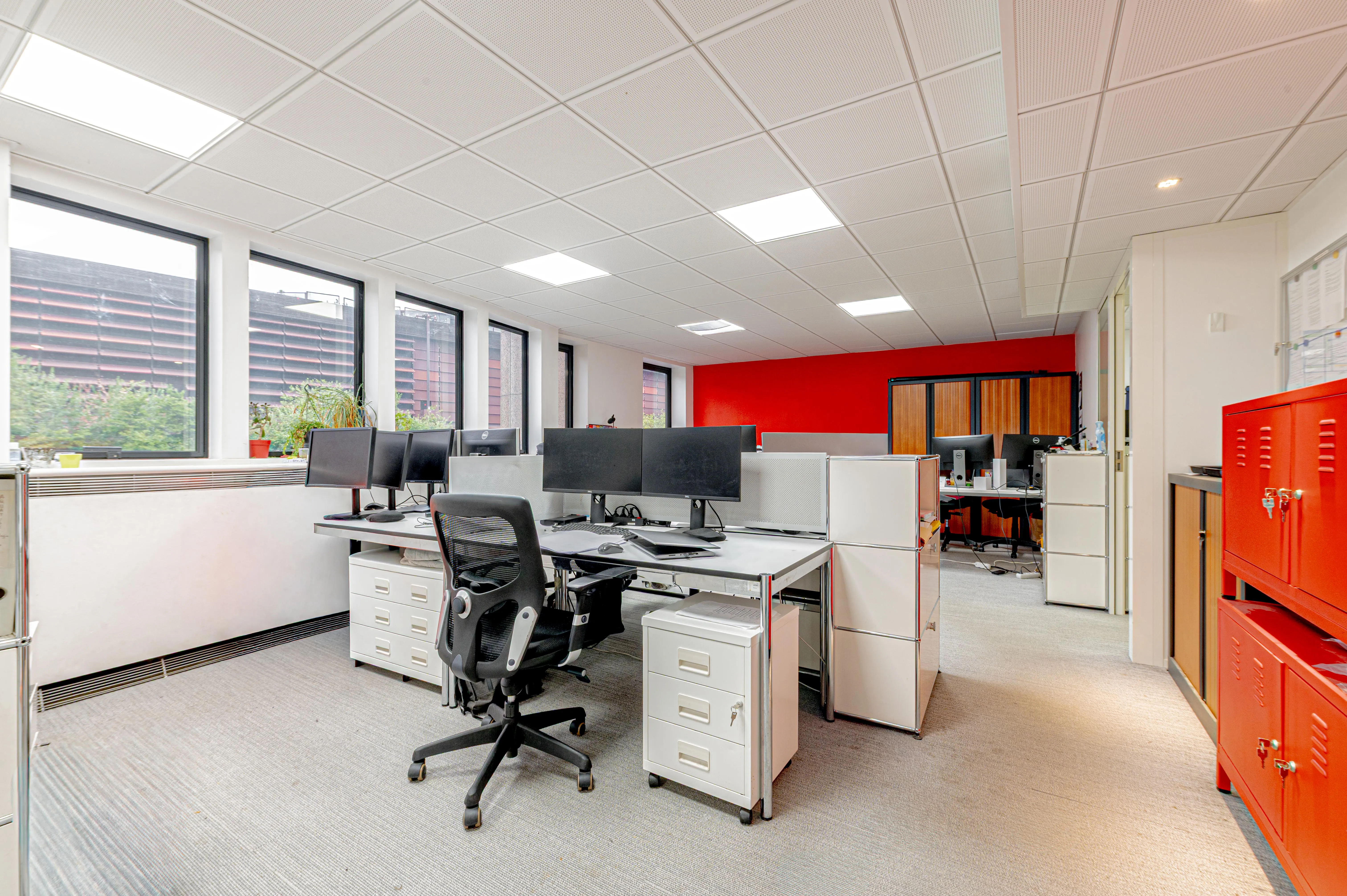 deux open spaces avec des bureaux et des chaises et une cuisine