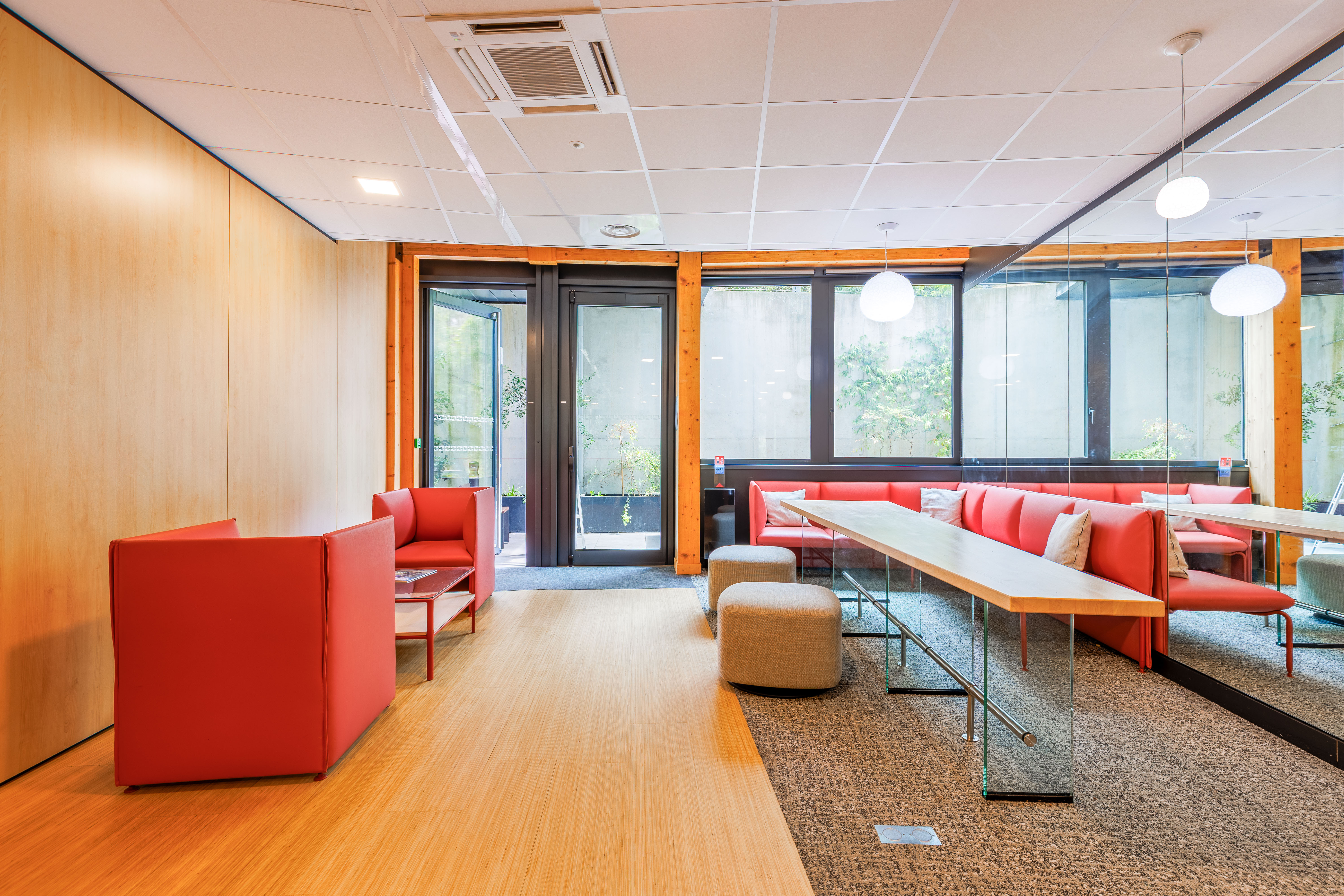des grands bureaux blancs avec des chaises, des phones booth pour 4 personnes, une salle détente avec des plantes et un babyfoot, des open spaces et des bureaux avec des cloisons