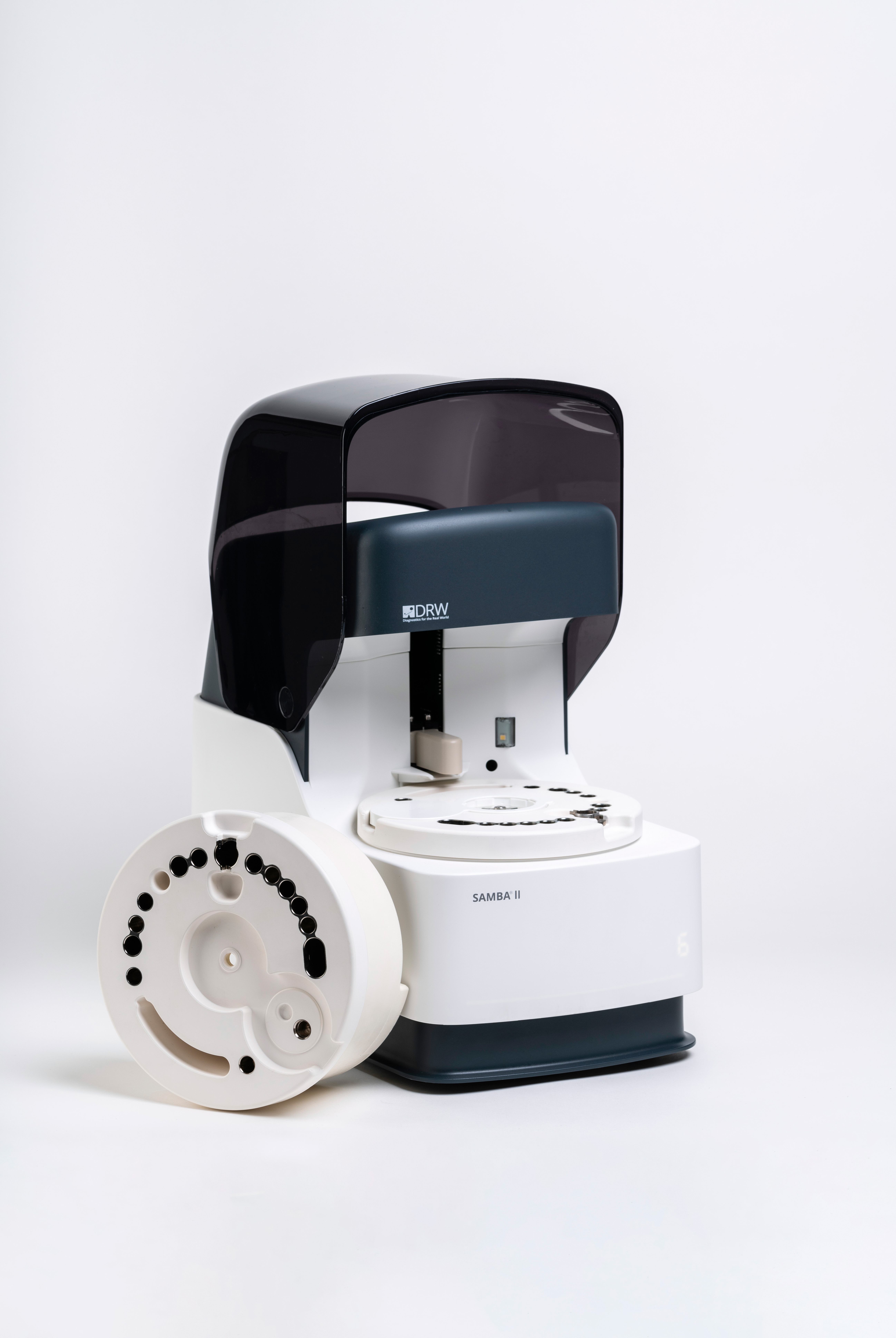 DRW SAMBA II laboratory diagnostic device with a detachable circular white component featuring multiple black holes on a white background.