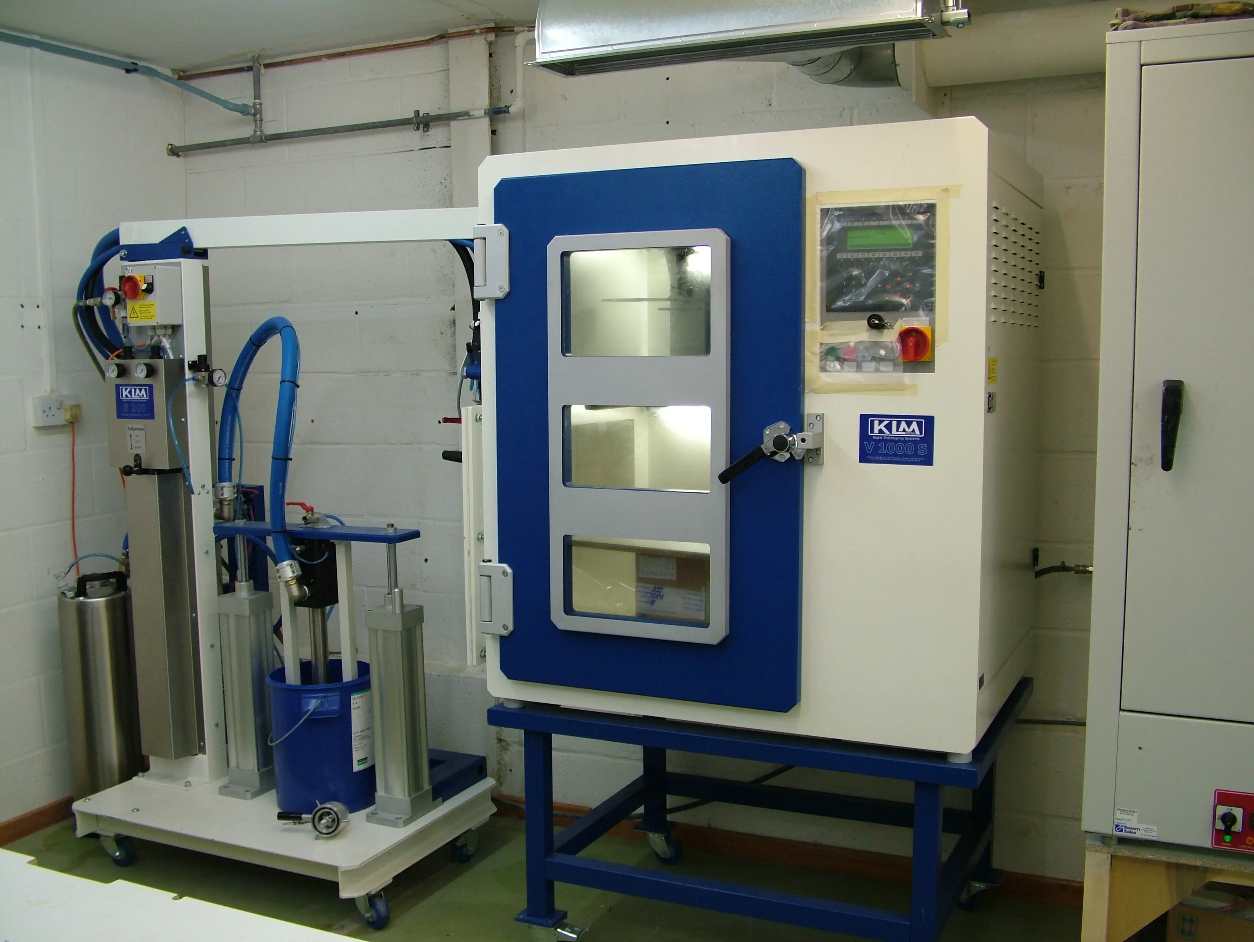 Vaccum casting machine with oven with control panel and connected equipment in a casting room.