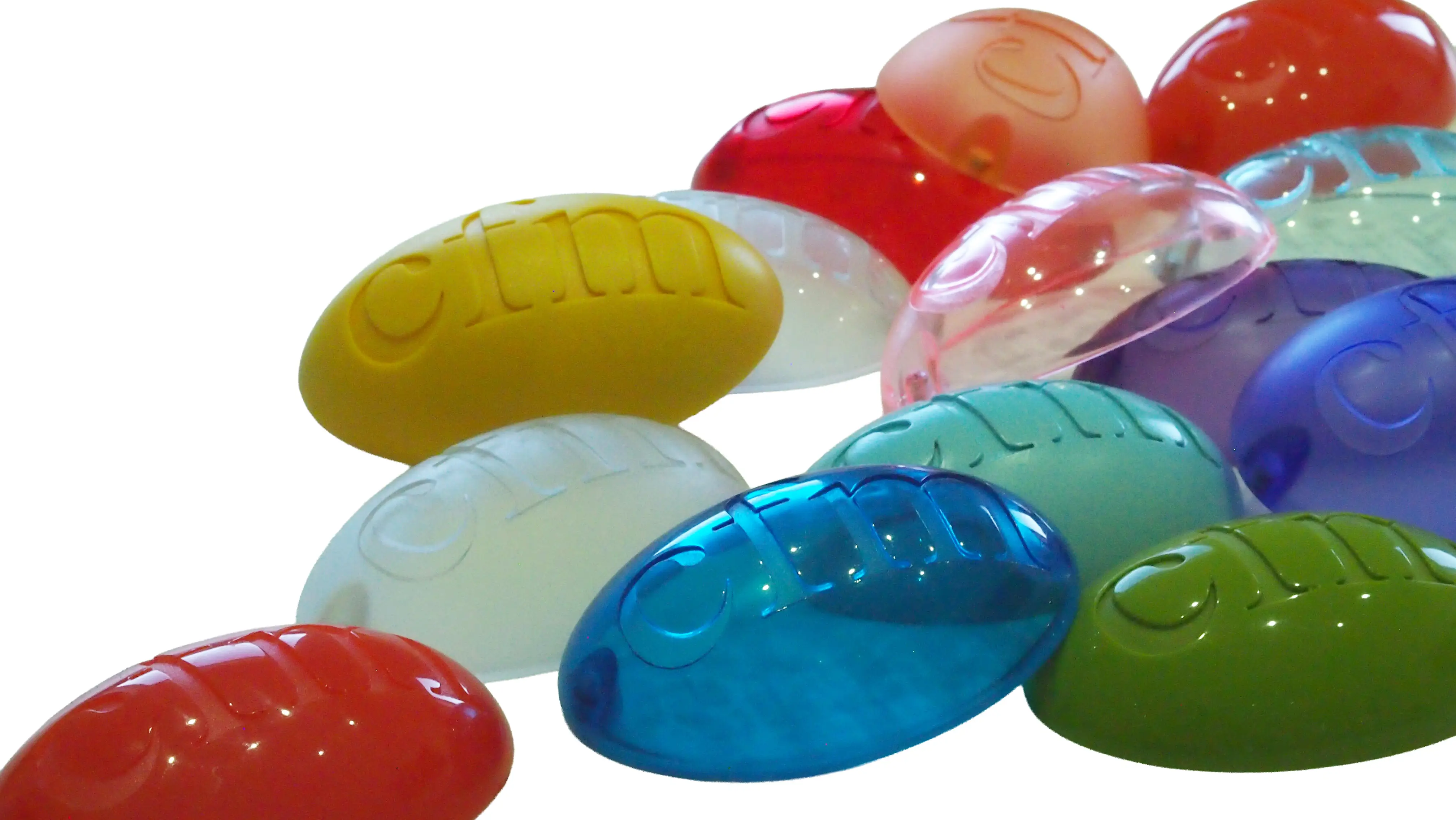 Close-up of colorful translucent CFM logo samples made of cast PU resins impression trays arranged in a pile on a white background.