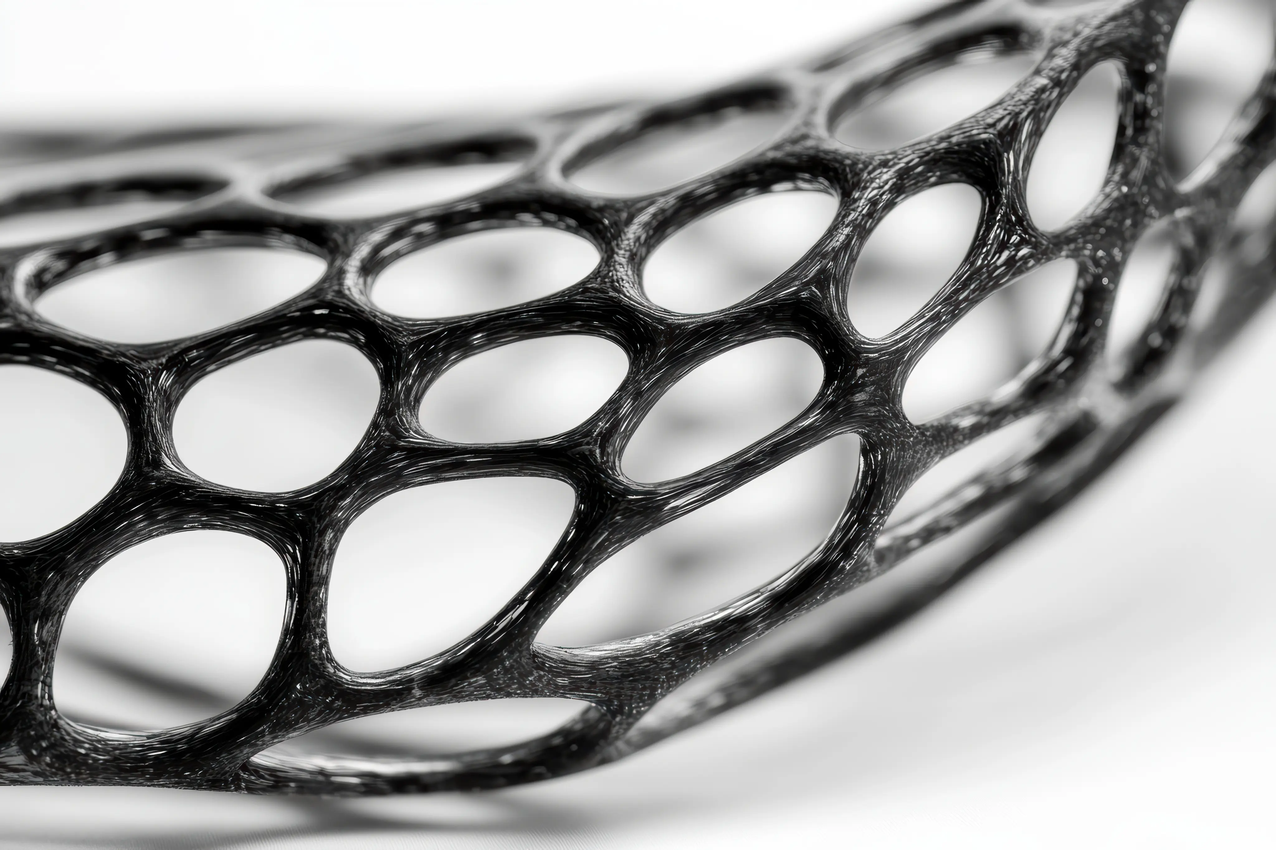 Close-up of a black, flexible, structure with interconnected oval-shaped holes.