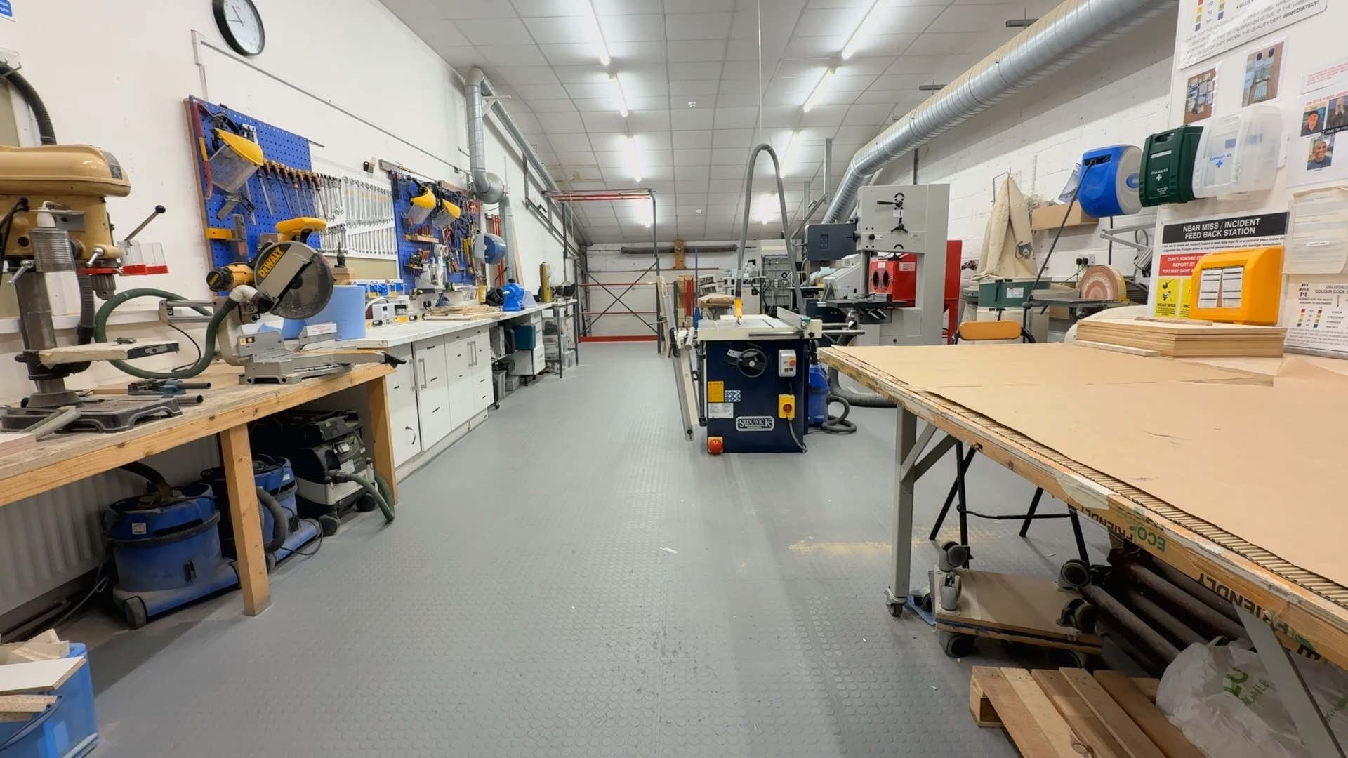 Wide view of a clean, organized woodworking shop with various tools, machines, and workbenches.