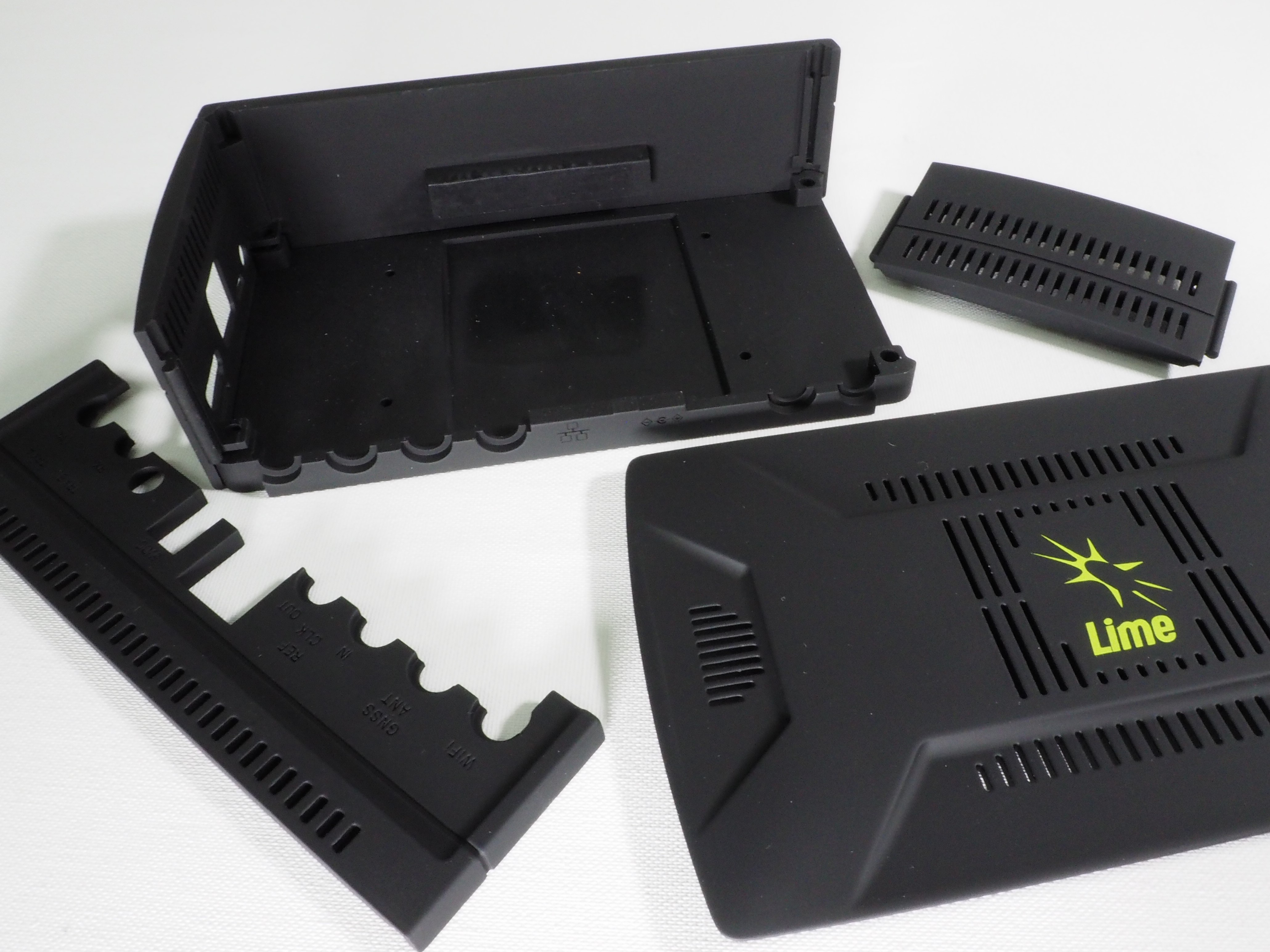 Black plastic electronic device parts including a branded cover with the Lime logo, laid out on a white surface.