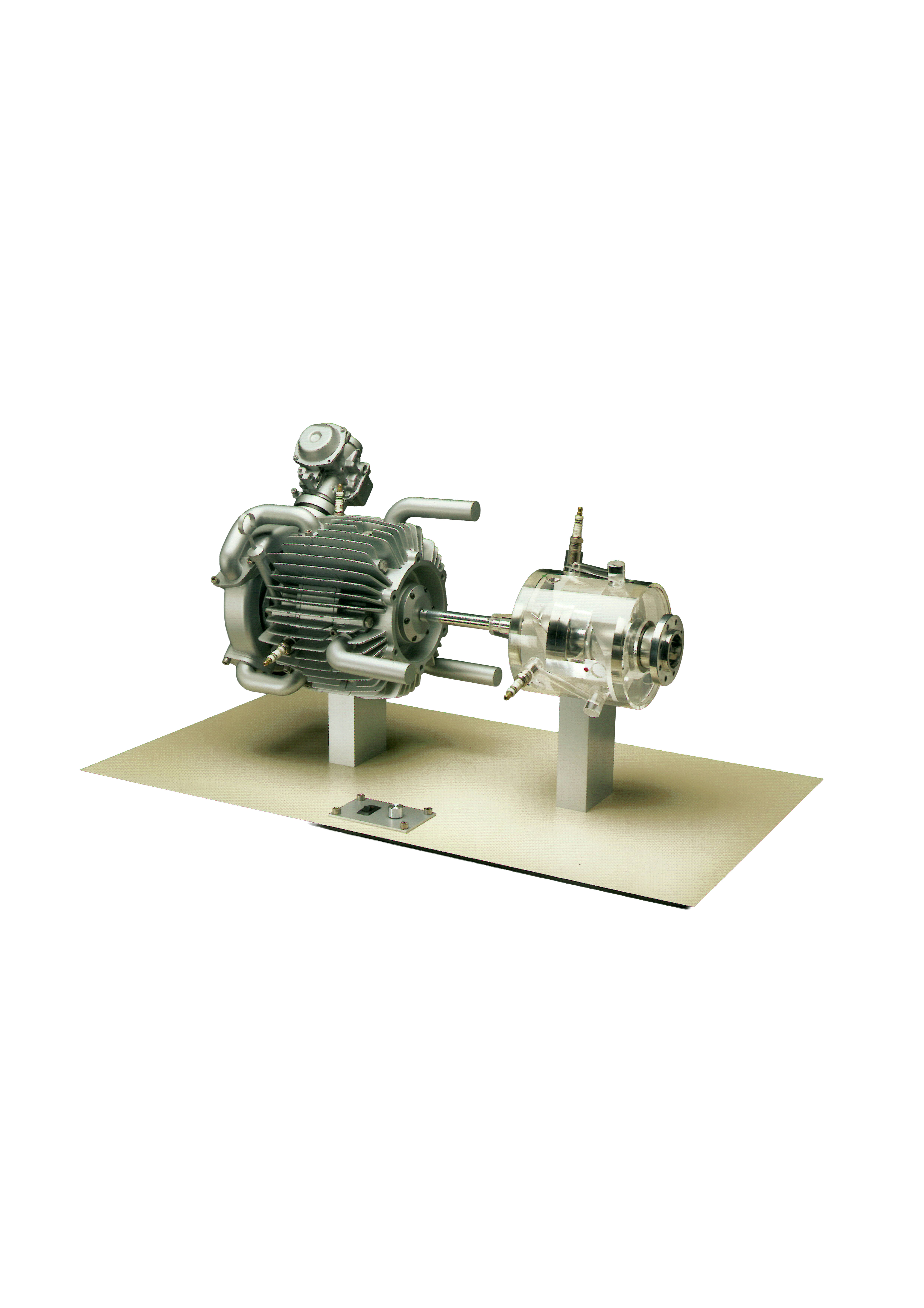 Metallic rotary engine model mounted on a beige platform showing detailed housing, fins, and connected transparent casing on two supports.