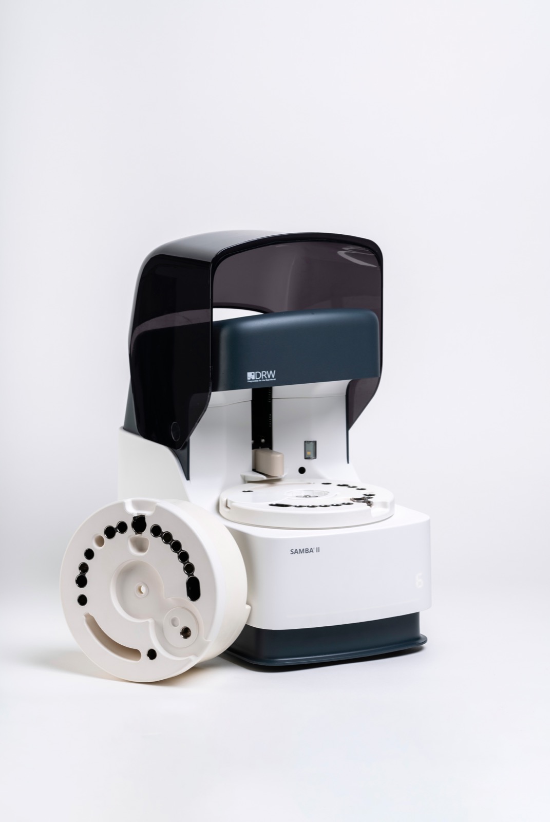 DRW SAMBA II laboratory diagnostic device with a detachable circular white component featuring multiple black holes on a white background.