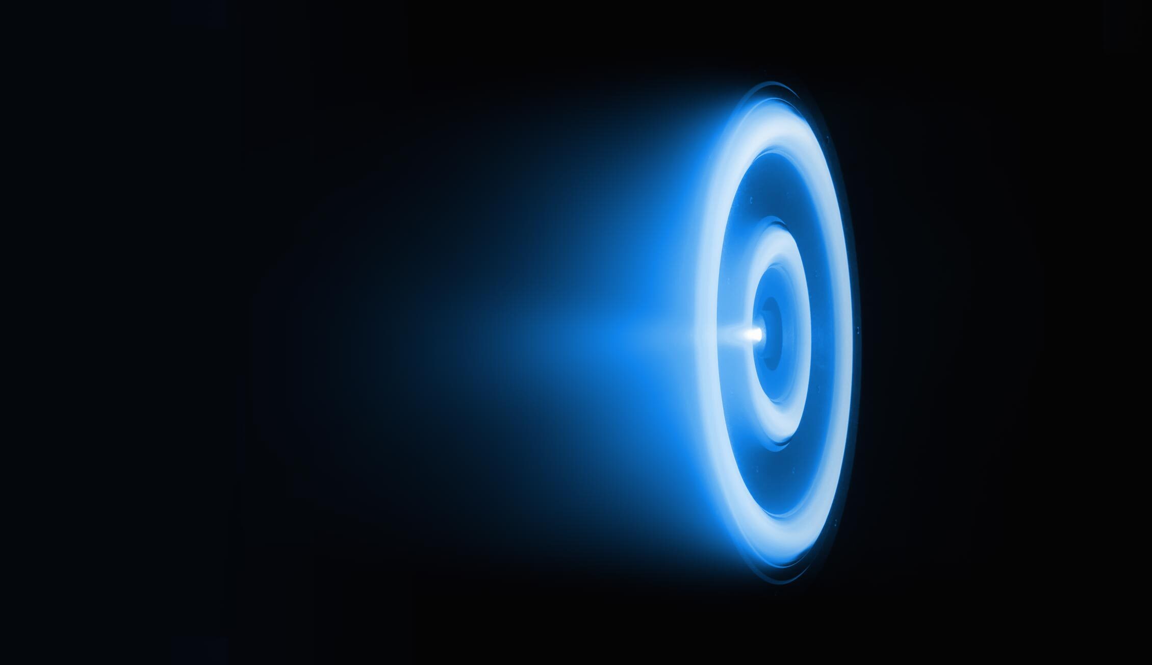 Engineers working inside the K2 Space manufacturing facility, assembling satellite components behind large glass panels