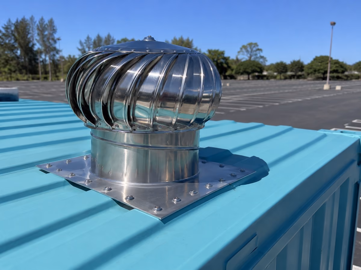 Chrome turbine roof vent on top of a teal shipping container