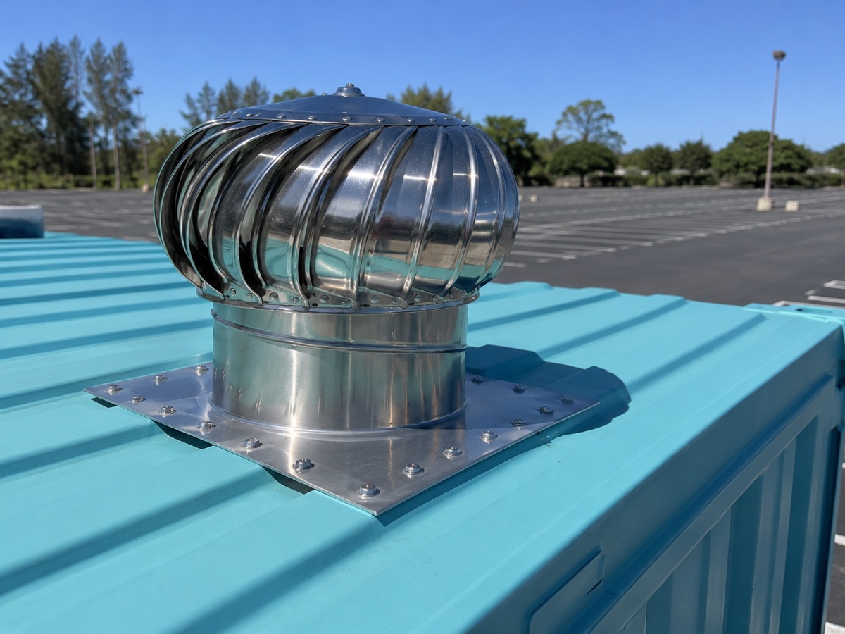 Chrome turbine roof vent on top of a teal shipping container