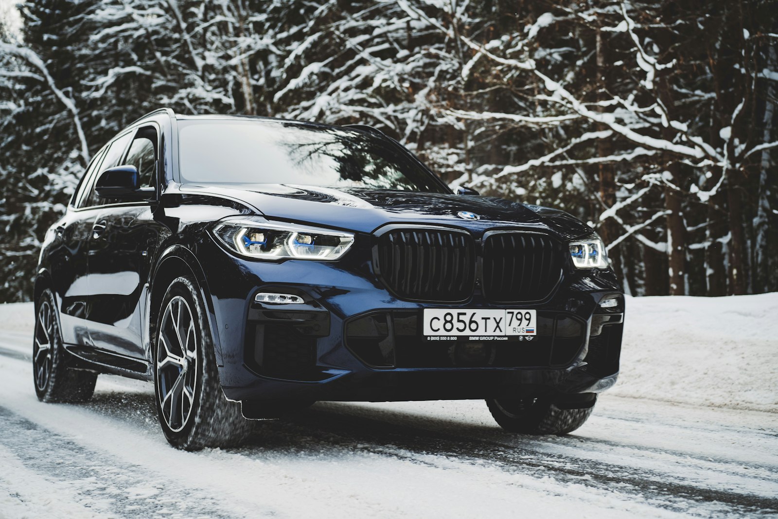 Black BMW SUV with xDrive driving down a snowy road in winter