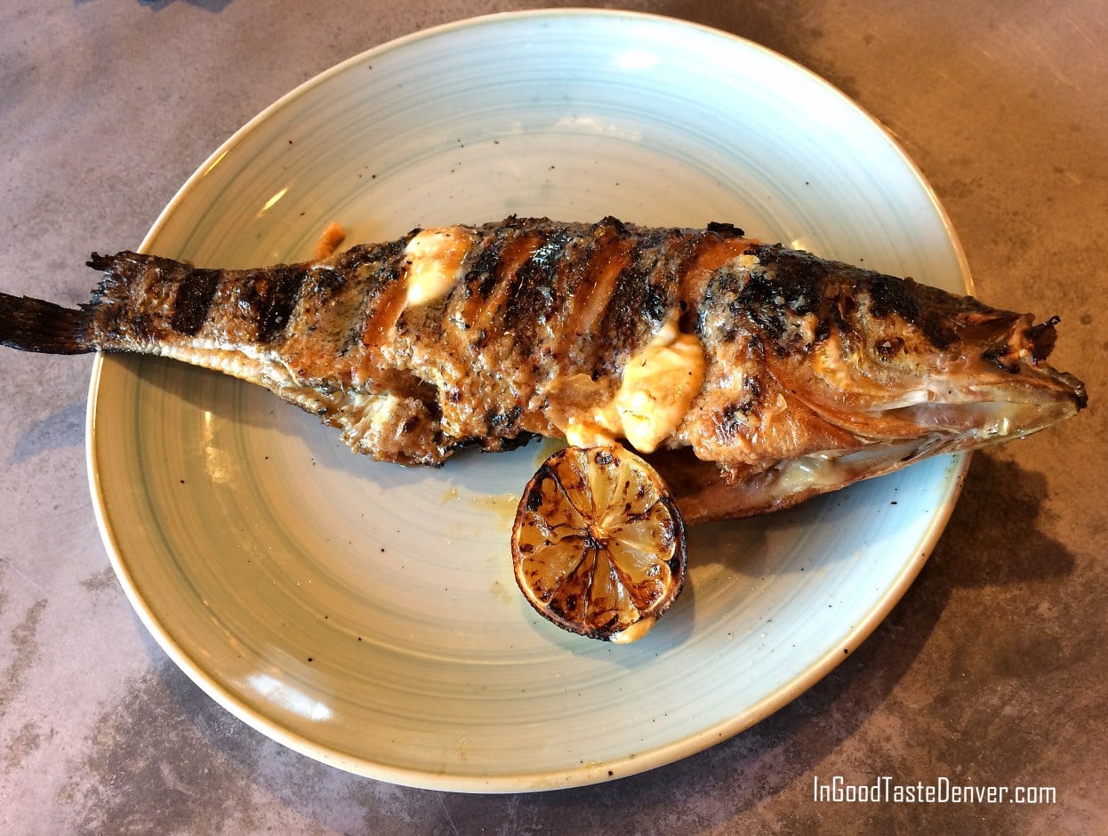 Whole grilled bass fish on a plate