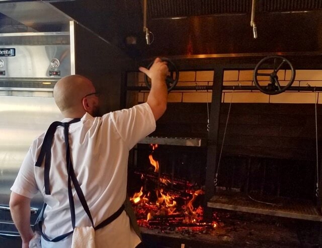Chef standing in front of wood fire grill