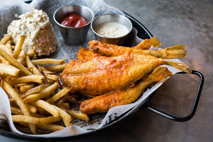 Plate of fried fish, smoked fish dip and french fries with ketchup and tartar sauce in small cups