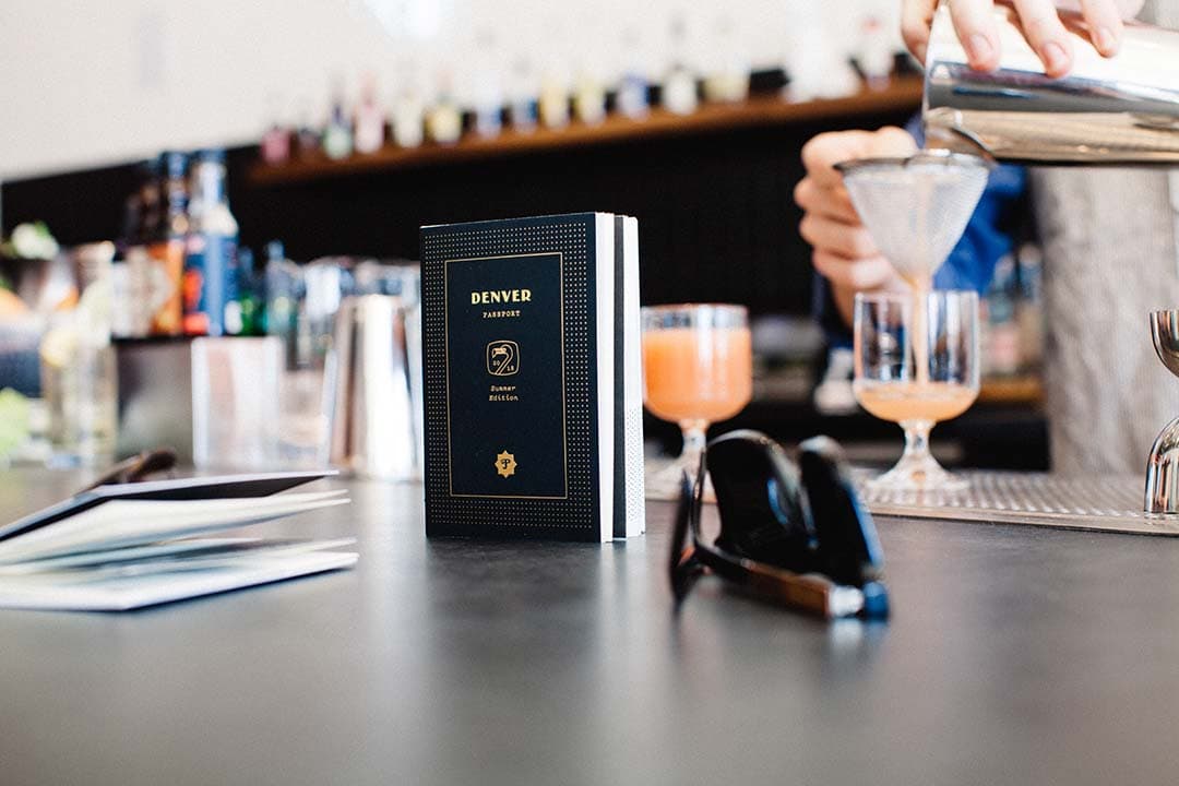 Denver passport booklet on a bar top with cocktails being poured