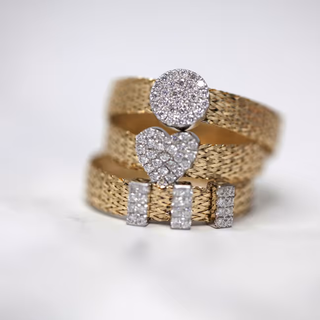 Gold ring with an intricate woven texture, adorned with diamond-studded circular, heart, and rectangular shapes.