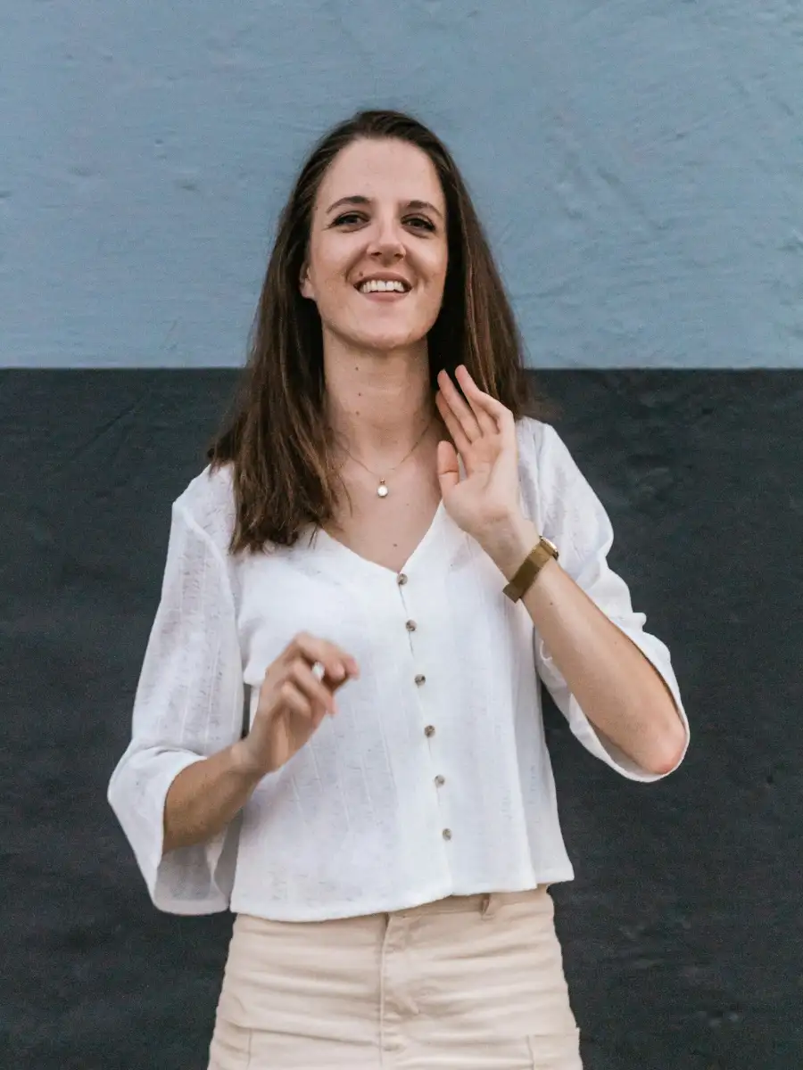 Woman smiling while holding a phone outdoors.