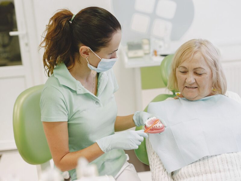 Full denture in an open storage case next to a glass of water on a warm nightstand