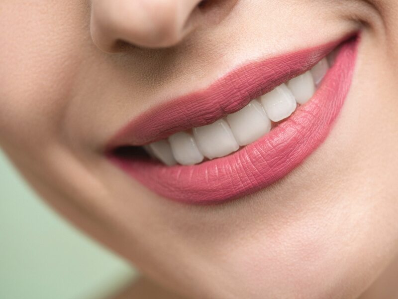Hand mirror and teeth whitening kit arranged on a cream-toned vanity in soft light