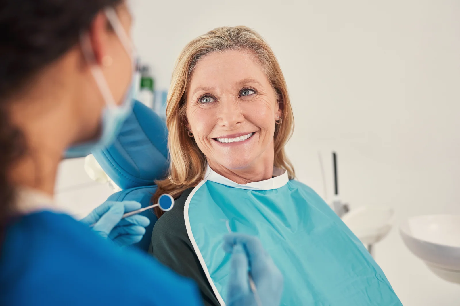 Dentista revisando las encías de una paciente sonriente en el sillón dental